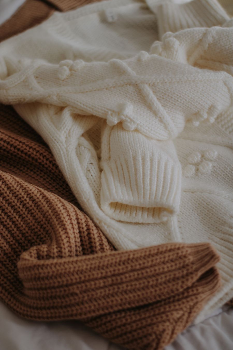 Cream and camel knitted jumpers folded in a stack