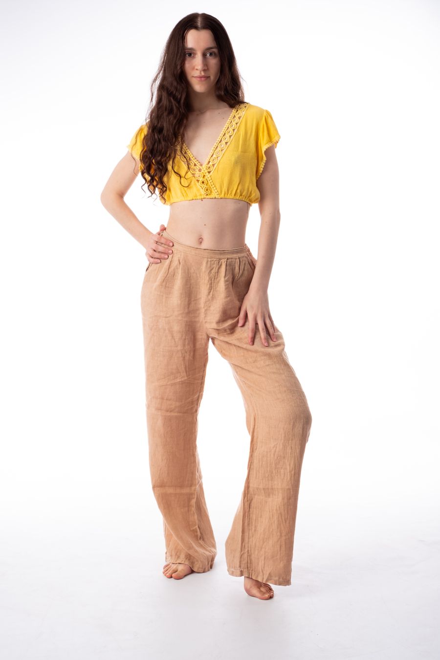 Wide-leg linen trousers in a warm sand tone, seen from the side