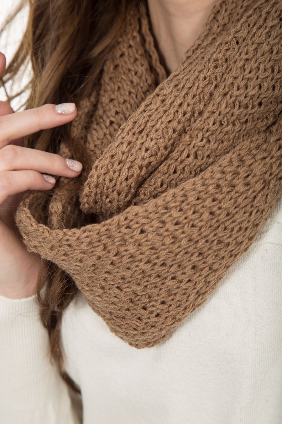 Hands wrapped in a chunky brown knitted scarf