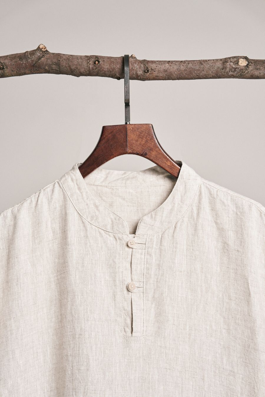 Collarless cream linen shirt on a wooden hanger