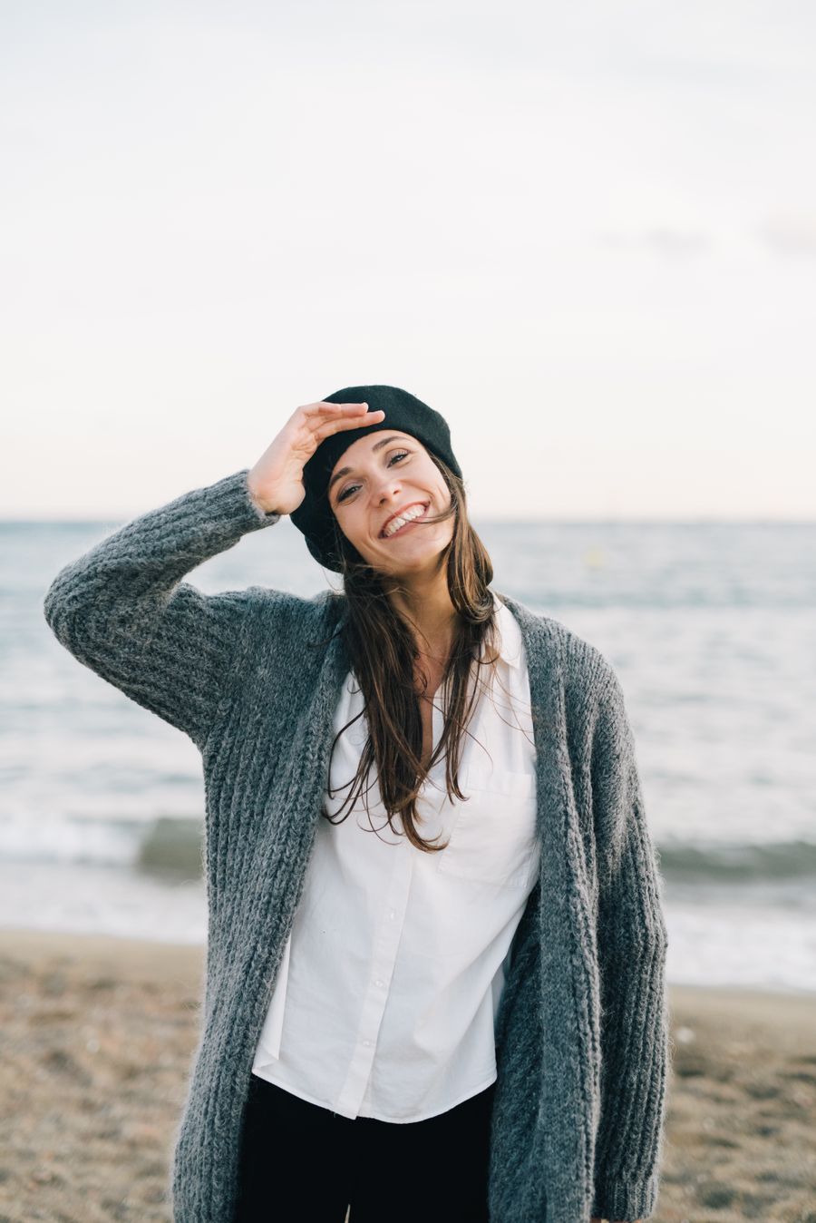 Smiling woman in an oatmeal knitted cardigan on a windy beach