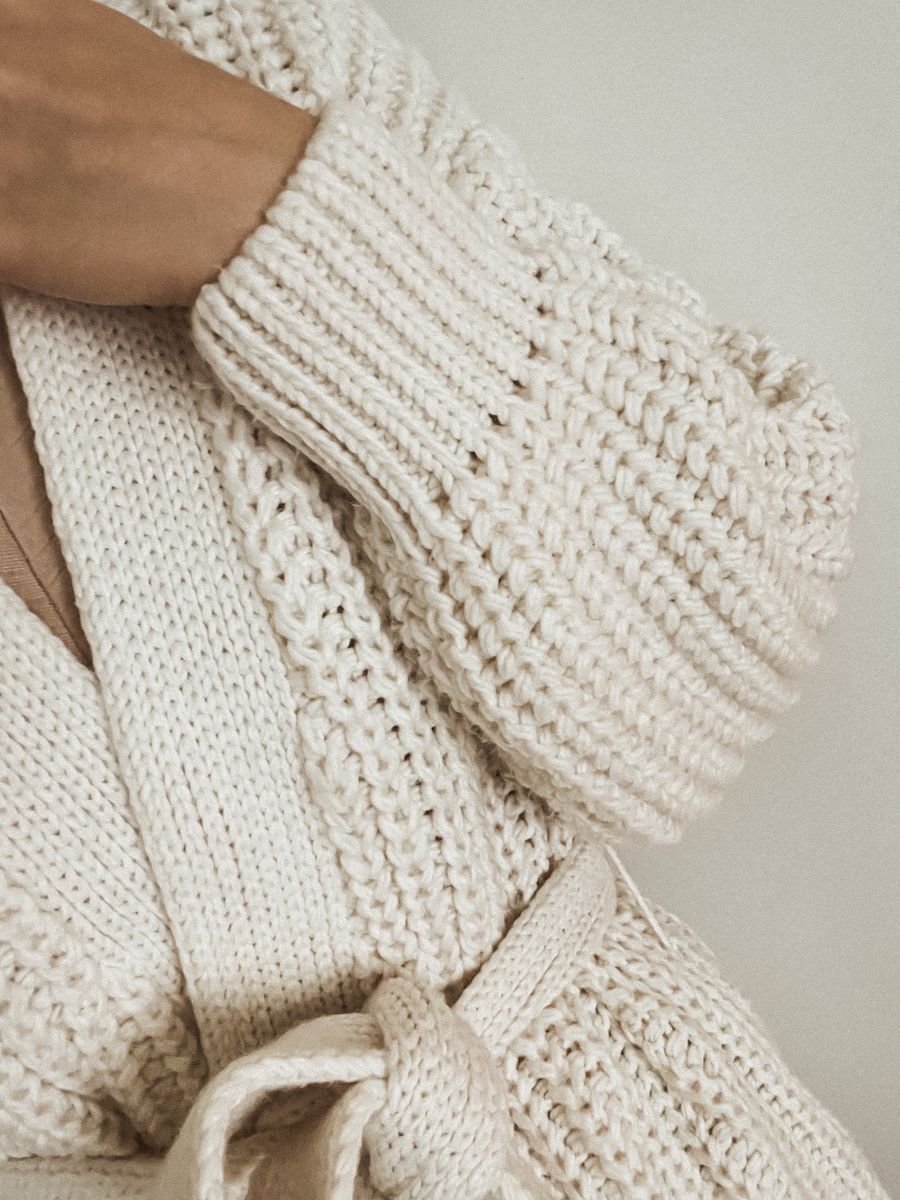 Close-up of a chunky cream cable-knit cardigan