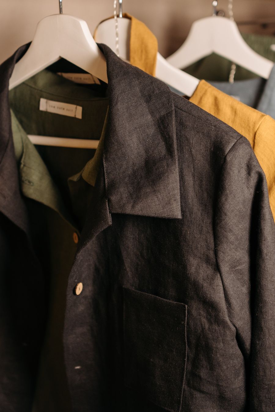 Dark linen work jackets hanging on a rail in a boutique