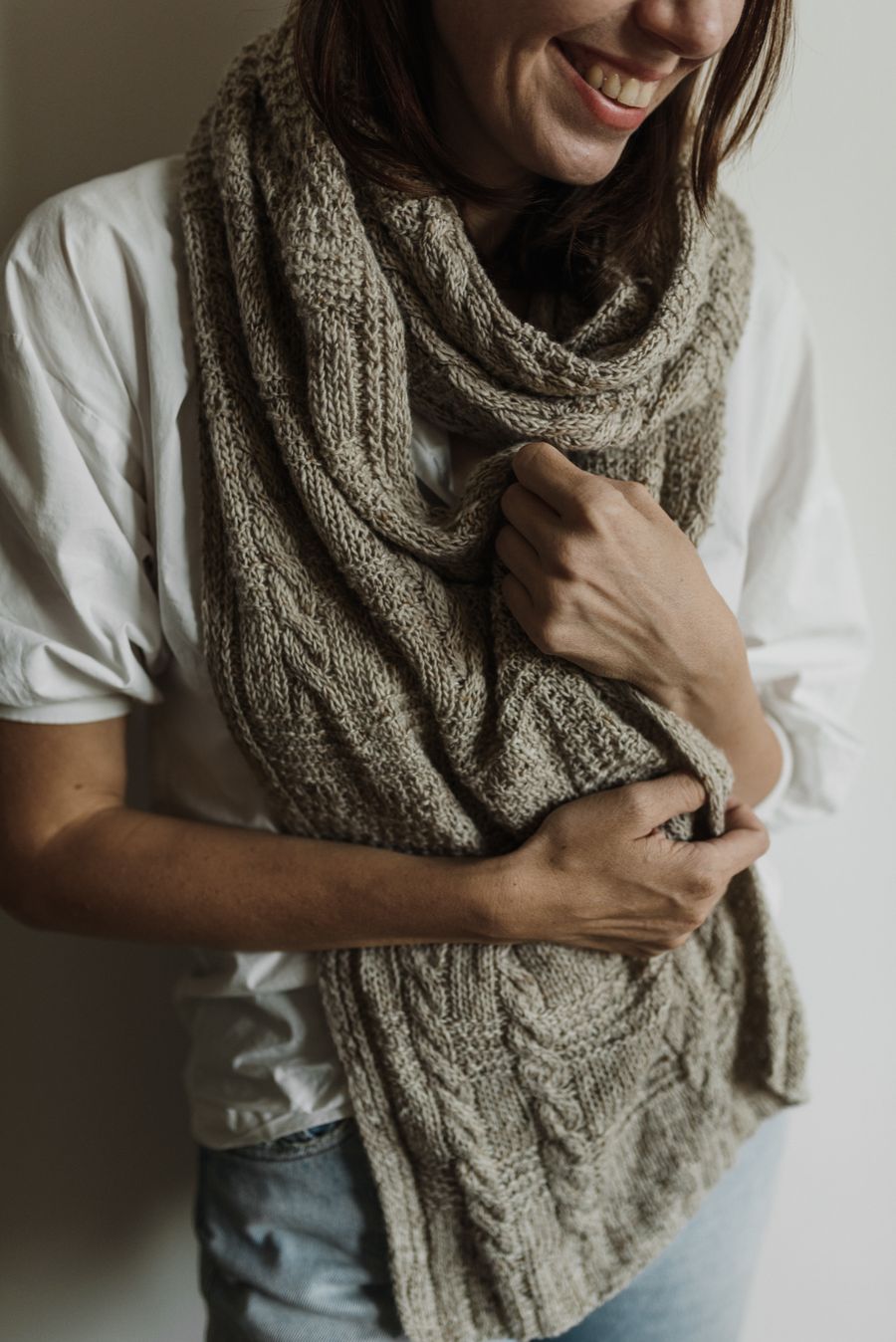 Woman holding a soft grey knitted scarf to her chest