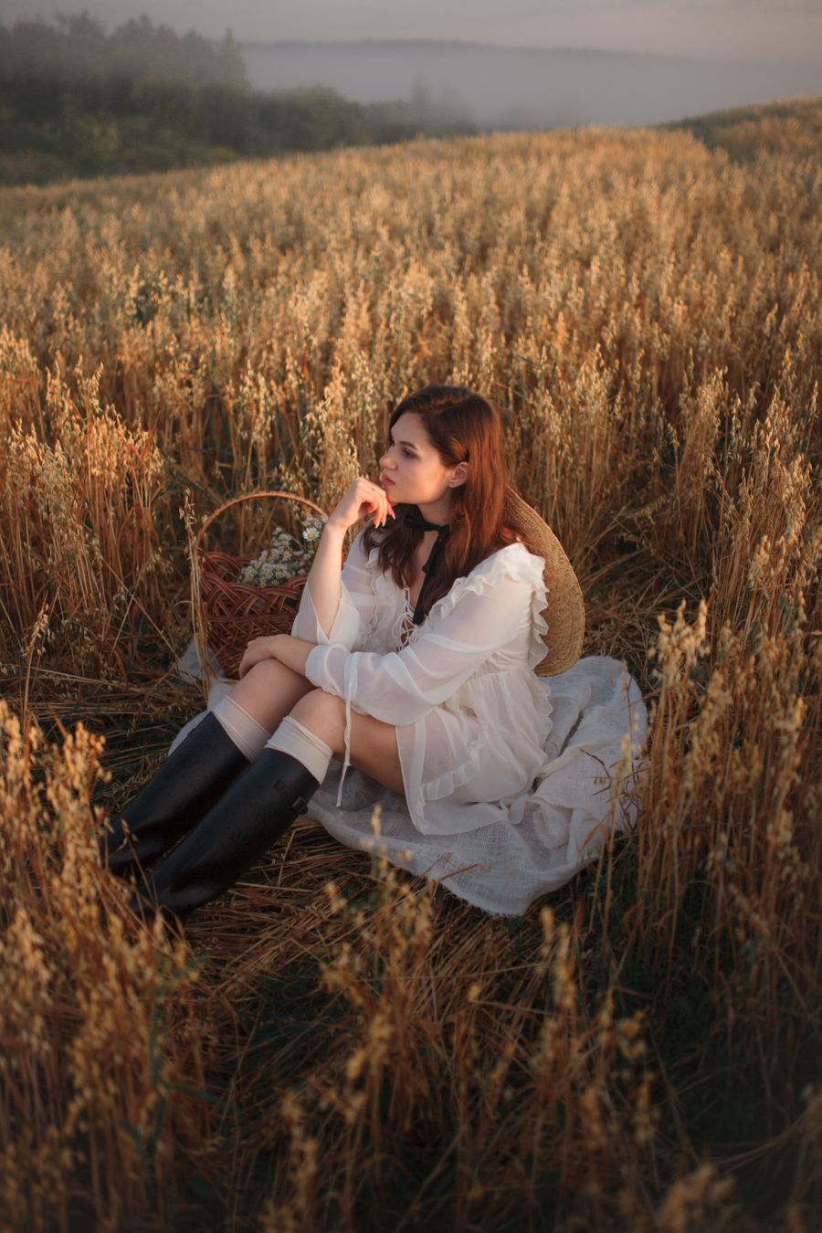 Woman in a white linen dress sitting in a golden wheat field